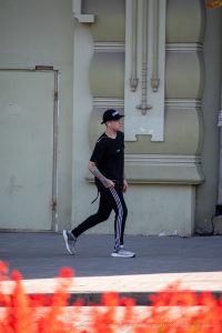 Фотография мужчины в черной кепке и спортивном костюме с татуировкой на предплечье на фоне ярких огней.