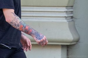 Крупный план татуировки на руке мужчины, выполненной в стиле японской татуировки Ирэзуми с изображением карпов кои и волн.