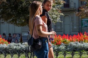 Фото тату на руке и плече девушки: реалистичный рисунок с изображением птицы и цветов в пастельных тонах.