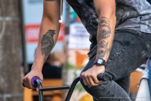 Фото крупным планом рук с детализированными татуировками ворона и черепов. Видны четкие линии и реалистичная прорисовка татуировок.