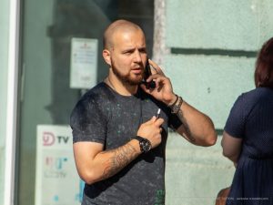 Фото мужчины с татуировками на руках, говорящего по телефону. На руках видны детализированные рисунки татуировок, включая черепа и другие символы.