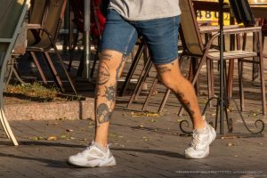 Фото тату на голени мужчины, демонстрирующее разнообразие рисунков, включая надписи и символы. Изображения выполнены в различных стилях и цветах.