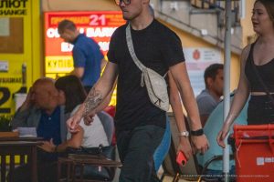 Фото тату: Черный ворон с красными брызгами на предплечье мужчины, выполненный в стиле графики. Детализированный рисунок татуировки.