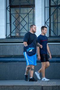 Фото тату на руках и ногах двух мужчин, идущих по улице. Видны детализированные рисунки татуировок в стиле традишнл.
