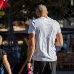 Фото татуировки на плече мужчины, изображающей французский флаг. Мужчина одет в спортивную одежду и держит поводок от собаки.