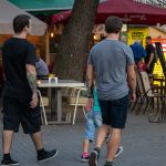 Фотография двух мужчин с татуировками на руках, идущих по улице. Татуировки выполнены в разных стилях, включая традиционный и графический.