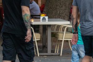 Фотография мужчины и ребенка с татуировками на руках. Татуировки выполнены в разных стилях, но объединены общей тематикой.
