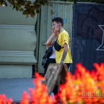 Фото молодого человека с татуировкой на руке, изображающей букет пионов в серой гамме. Современный стиль, городской пейзаж.