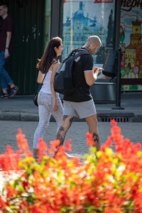 Фотография мужчины и девушки, идущих по улице, с видимыми татуировками на ногах. Татуировки выполнены в черном цвете, с использованием геометрических узоров и абстрактных рисунков.