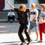 Фотография скейтбордиста в движении, с видимыми татуировками на руках. Татуировки выполнены в черном цвете, с геометрическими и абстрактными узорами.