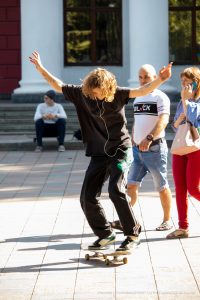 Фотография скейтбордиста в движении, с видимыми татуировками на руках. Татуировки выполнены в черном цвете, с геометрическими и абстрактными узорами.
