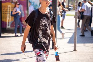 Фото мужчины с татуировкой на руке, идущего по улице. Стильный образ и детализированный рисунок татуировки.