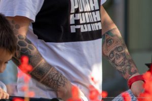 Фото тату на руке мужчины: реалистичный череп с глазом в треугольнике, окруженный брызгами краски. Черно-красная цветовая гамма, детальная проработка.