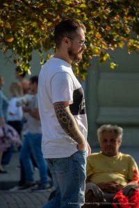 Фото мужчины с татуировкой на руке в стиле геометрии, снятое сбоку. Видны темные узоры из шестиугольников на предплечье. Мужчина смотрит в сторону.