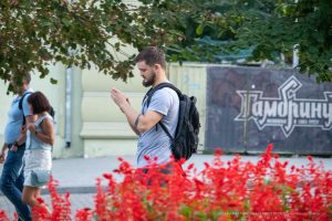 Фото мужчины с татуировкой на руке, идущего по улице. Современный городской стиль и минималистичный рисунок татуировки.