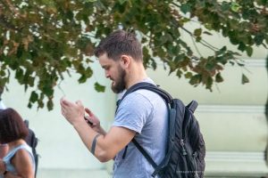 Фото мужчины с татуировкой на руке, идущего по улице. Современный городской стиль и минималистичный рисунок татуировки.