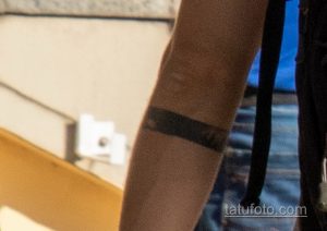 Фотография мужской руки с простой чёрной татуировкой в виде браслета. Татуировка выполнена в виде широкой полосы, обхватывающей запястье.