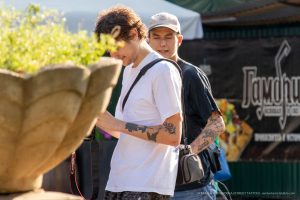 Фото тату: мужчина-фотограф с татуировками на руках, смотрит в камеру. Видны небольшие рисунки татуировок на предплечье.