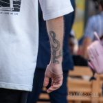 Фотография мужской руки с татуировкой в виде змеи. Татуировка выполнена в чёрных тонах и имеет детализированную прорисовку чешуи и изгибов тела змеи.