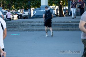 Фото тату корабля на икре мужчины, идущего по лестнице. Черно-серый рисунок татуировки в реалистичном стиле.