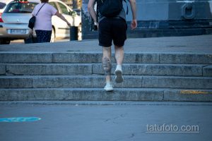 Фото тату: мужчина с татуировкой на ноге, поднимающийся по лестнице. Детализированный рисунок в стиле реализм.