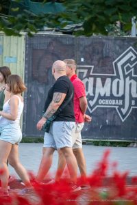 Фото тату: татуировка на плече и предплечье мужчины, изображающая череп и растительные элементы в черно-белой гамме.