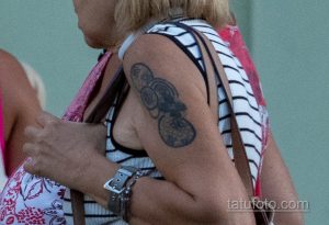 Фото тату на руке женщины, изображающее три темных круга, соединенных линиями. Татуировка выполнена в минималистичном стиле.