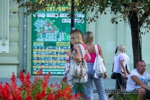 Фото тату на плече женщины, изображающее темный рисунок на фоне городской карты. Татуировка выглядит стильно и привлекательно.