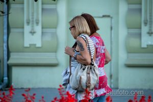 Фото тату на плече женщины, демонстрирующее темный рисунок. Татуировка выполнена в реалистичном стиле и выглядит элегантно.