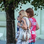 Фото тату на плече женщины в полосатой майке. Татуировка выполнена в темных тонах и частично видна под одеждой.