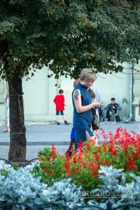 Фотография женщины с татуировкой на плече, держащей ребенка. На плече виден изящный черный цветочный орнамент, выполненный в графическом стиле.