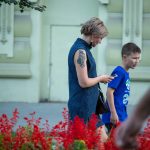 Фотография женщины с татуировкой на руке и ребенком рядом. Татуировка представляет собой темный орнамент, расположенный на плече.