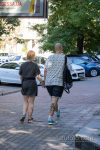 Фото мужчины с татуировкой на ноге, идущего по улице. Татуировка выполнена в темных тонах и видна из-под шорт.