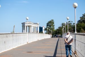Вид на Одесскую набережную с моста. Прохожие, фонари и архитектура создают атмосферу морского города.