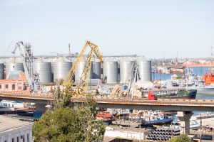 Фотография городского пейзажа с видом на порт, промышленные объекты и транспортную инфраструктуру.