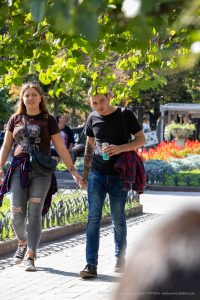 Фотография пары, прогуливающейся в парке. У мужчины на предплечье видна татуировка с детализированным рисунком.