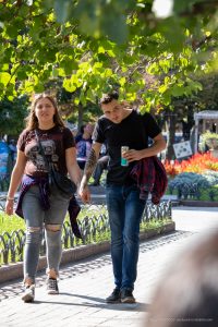 Фотография пары, прогуливающейся в парке. У мужчины на предплечье видна татуировка с детализированным рисунком.