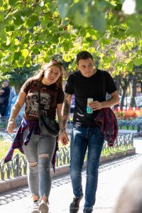 Фотография пары, прогуливающейся в парке. У мужчины на предплечье видна татуировка с детализированным рисунком.