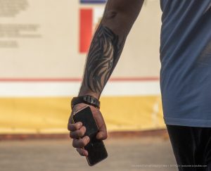 Фото тату: Черный племенной узор, покрывающий предплечье мужчины. Детализированный рисунок с острыми линиями и геометрическими формами.