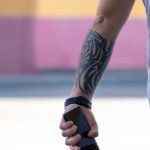 Фото татуировки: крупный план племенного узора в черных тонах на предплечье мужчины. Детализированный рисунок татуировки в стиле трайбл.