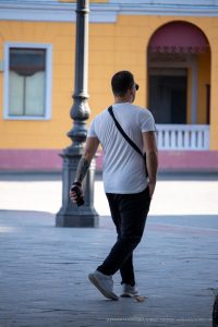 Фотография мужчины с татуировкой на предплечье, идущего по улице. Татуировка выполнена в стиле трайбл, черного цвета.