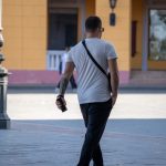 Фотография мужчины с татуировкой на предплечье, идущего по улице. Татуировка выполнена в стиле трайбл, черного цвета.