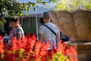 Фото тату на плече мужчины: полинезийская графика, выполненная в черном цвете. Мужчина стоит на улице, окруженный зеленью и другими людьми.