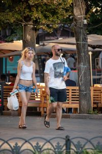 Фотография мужчины с татуировкой на предплечье, идущего по улице с девушкой. Татуировка выполнена в стиле трайбл, черного цвета.