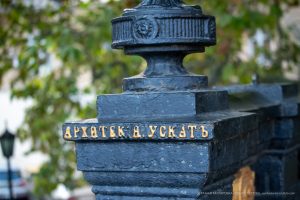 Фотография детали архитектурного сооружения с надписью "Архитектор А. Ускать". Крупный план, текстура камня, золотые буквы.