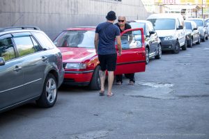 Фотография мужчины, открывающего дверь красного автомобиля, с видимой татуировкой на ноге.