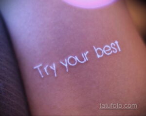 Фото тату: белая надпись "Try your best" на руке, выполненная каллиграфическим шрифтом. Мотивирующая татуировка для тех, кто верит в свои силы.