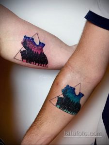 Фото парных тату с изображением леса и звездного неба в треугольнике. Рисунки выполнены в темных тонах с яркими акцентами звезд и галактик.
