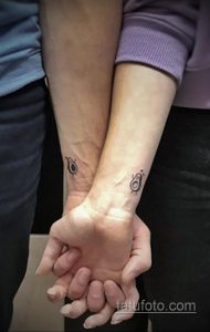 Фото тату на запястьях пары: стилизованные изображения половинок авокадо, вместе образующих целое. Минималистичный дизайн, выполненный в черном цвете с небольшими зелеными акцентами.