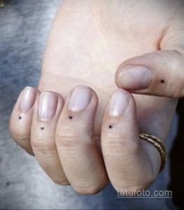 Фото тату: набор из нескольких маленьких черных точек, нанесенных на пальцы руки. Простой и элегантный дизайн для любителей минимализма.